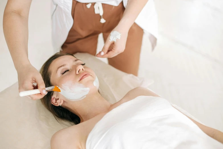 woman in bed with white facial mask on top of her face