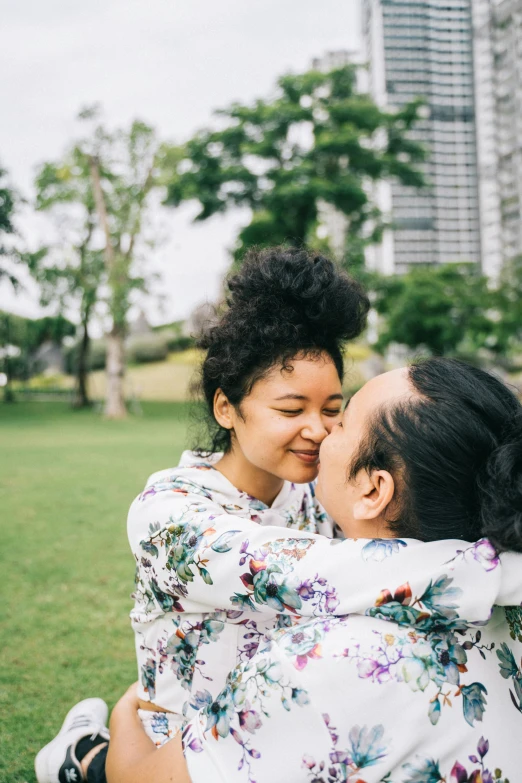 a young couple is hugging while one person in a park