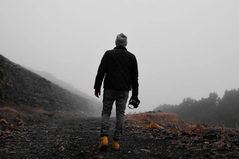 man walking on hill in heavy weather with umbrella