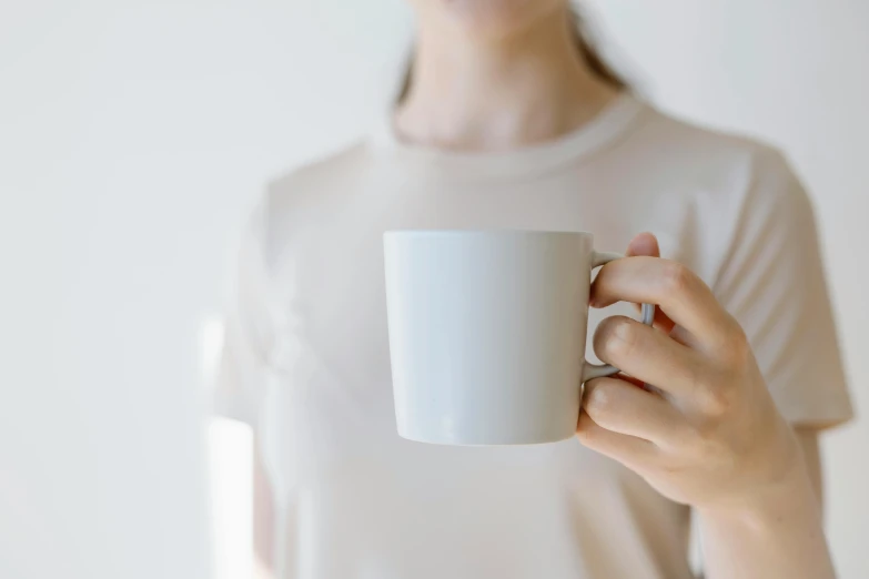 a woman holding up a white coffee cup