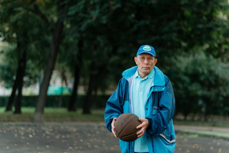 a man wearing a blue rain jacket holding a basketball