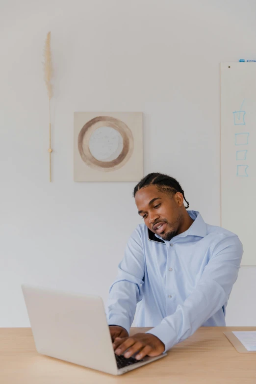 a man talking on a phone and working on a laptop