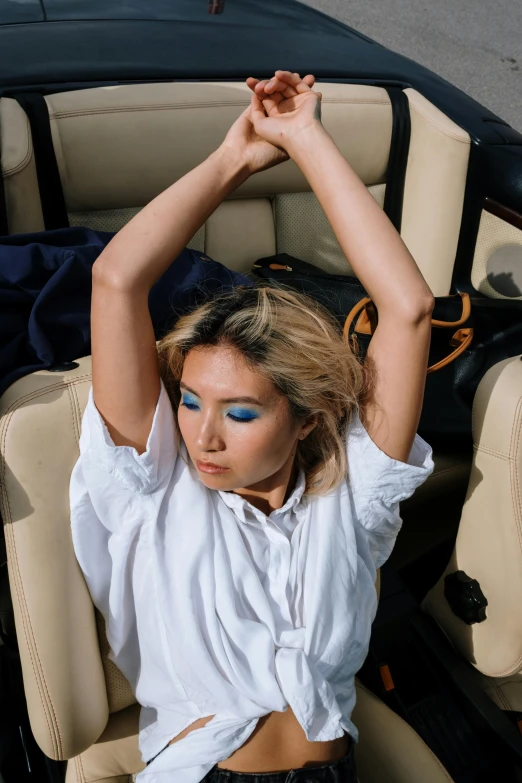 a model with a blue eye and white shirt posing in a black and beige chair