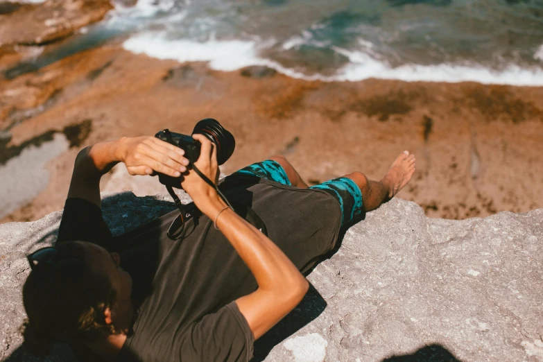 a man that is holding a camera near the ocean