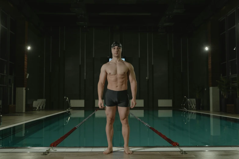 a man wearing black swimming trunks and no pants is standing in front of a pool