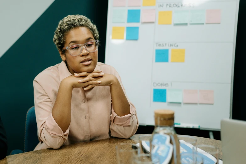 a person in glasses sitting at a wooden table