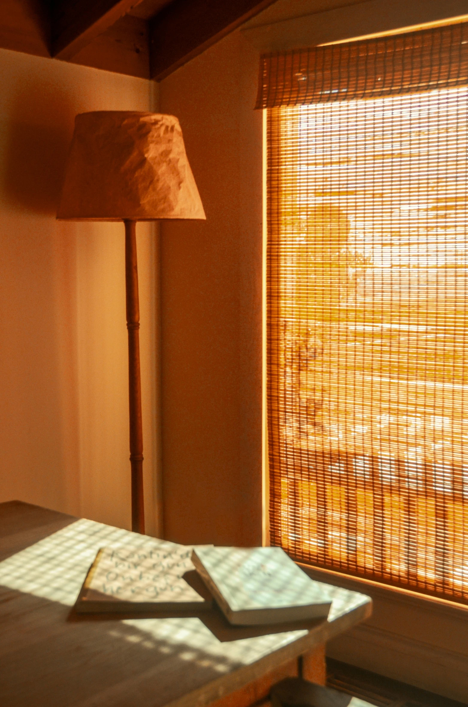 a lamp in front of a window and books sitting on a table