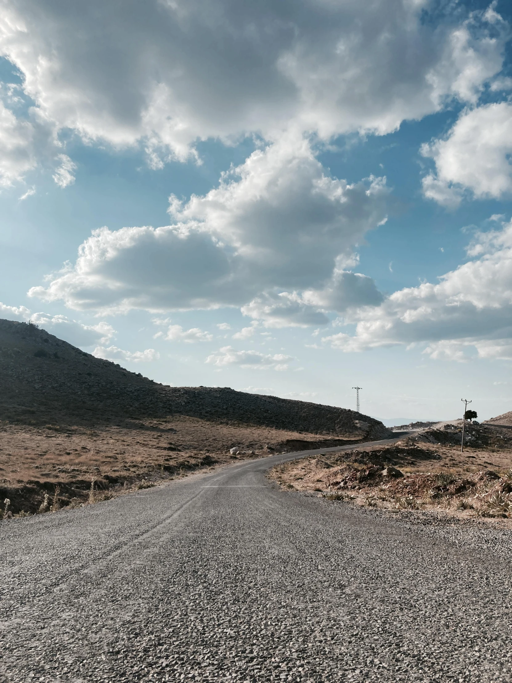 the sky has some white clouds over a dirt road