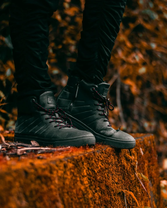 the foot and ankles of a man standing on a cement ledge