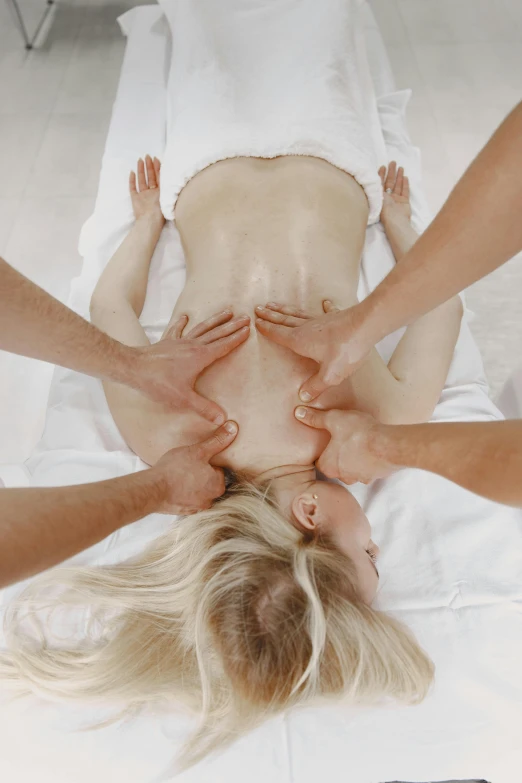 two women are touching their backs together on a white blanket