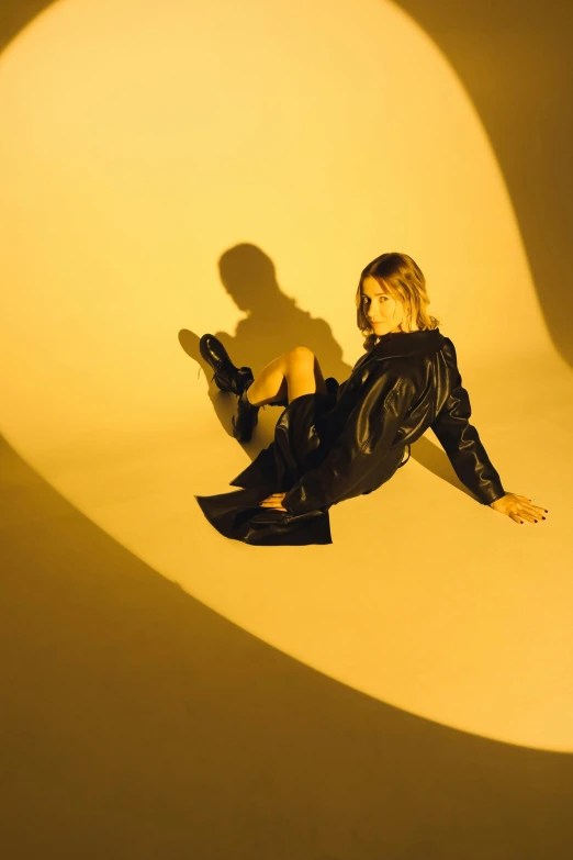 a woman in black is sitting on a white surface