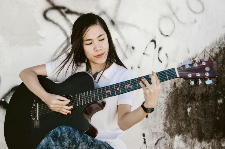 a woman holding an acoustic guitar against a white background