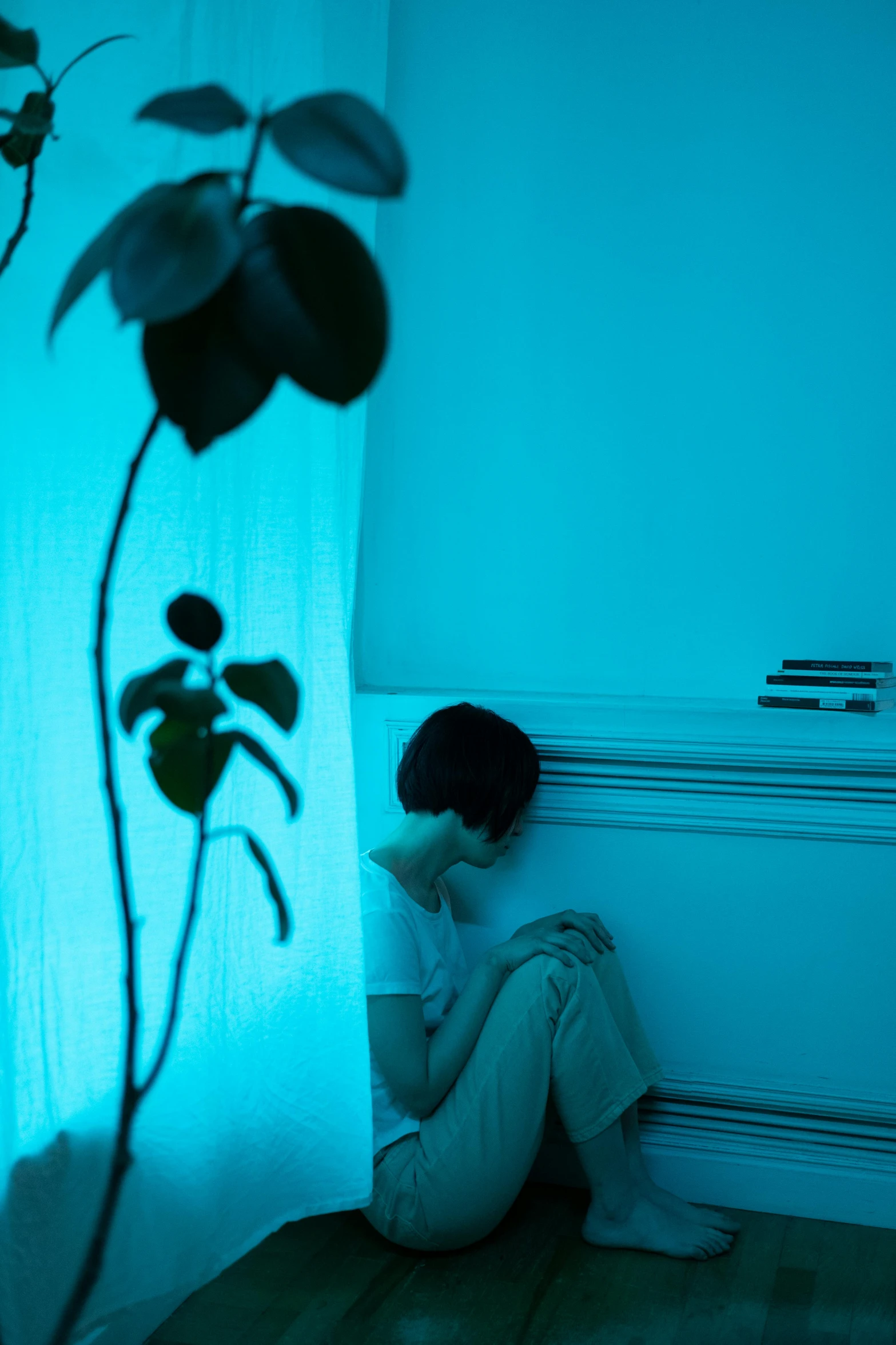 a person with their hands on the floor sits on the floor in front of a window