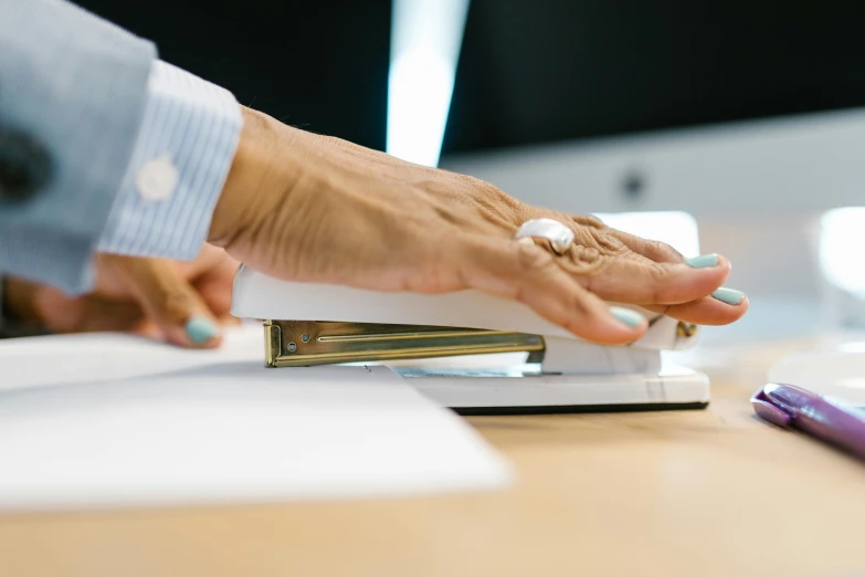 the business women is holding onto the business binder and has one hand on the desk with a ball