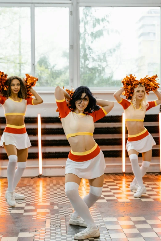 four cheerleaders are performing on a tiled floor