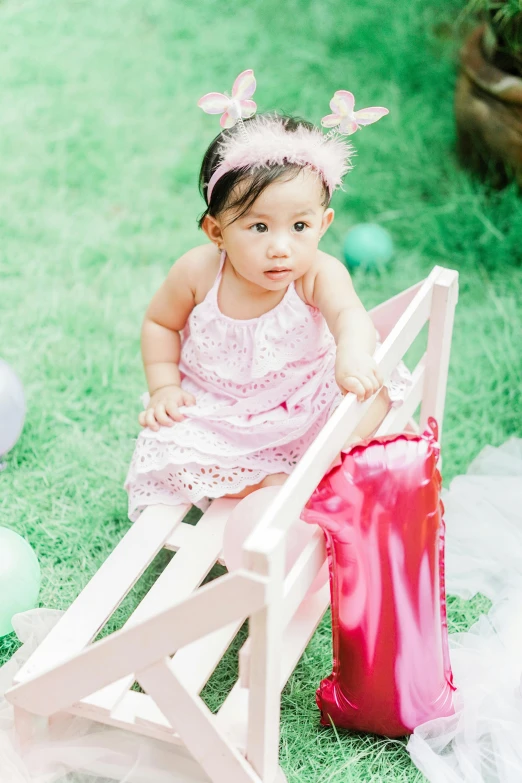 a  dressed in pink with erflies sitting on a wooden chair