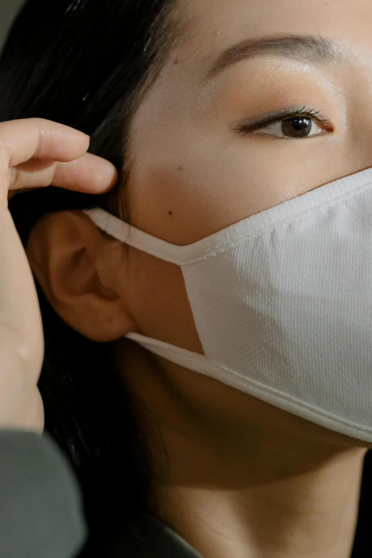a woman putting a protective mask on her face