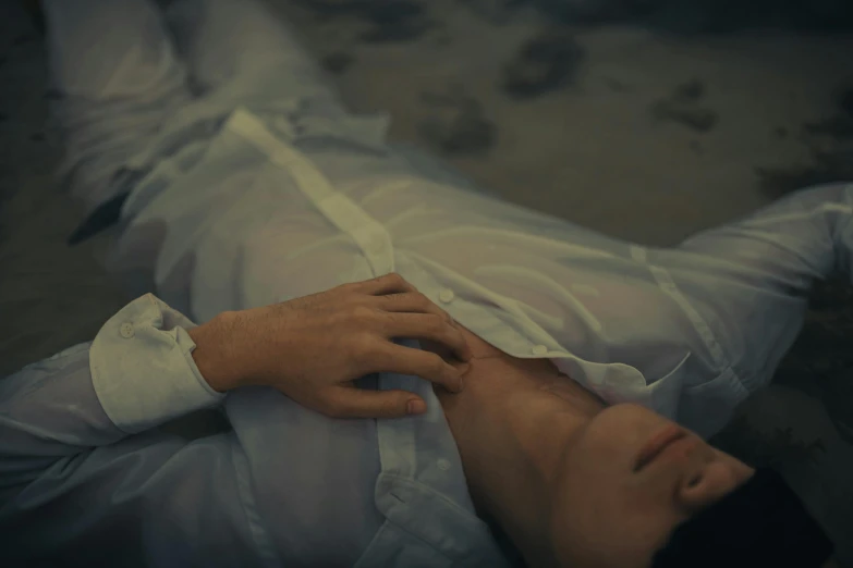 a man lying on a floor wearing a white shirt