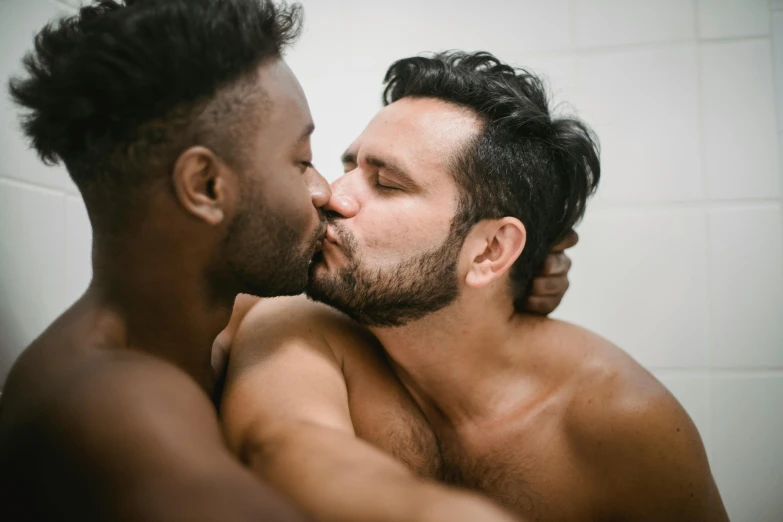 a couple of men kissing each other in front of a mirror