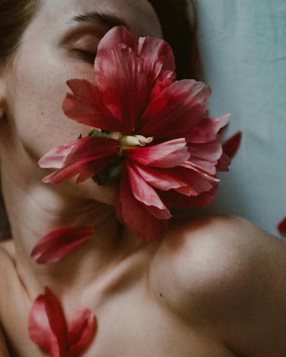the woman is sleeping on her side holding red flower in her mouth