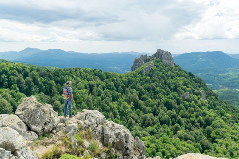 two people are standing on a mountain overlooking the valley