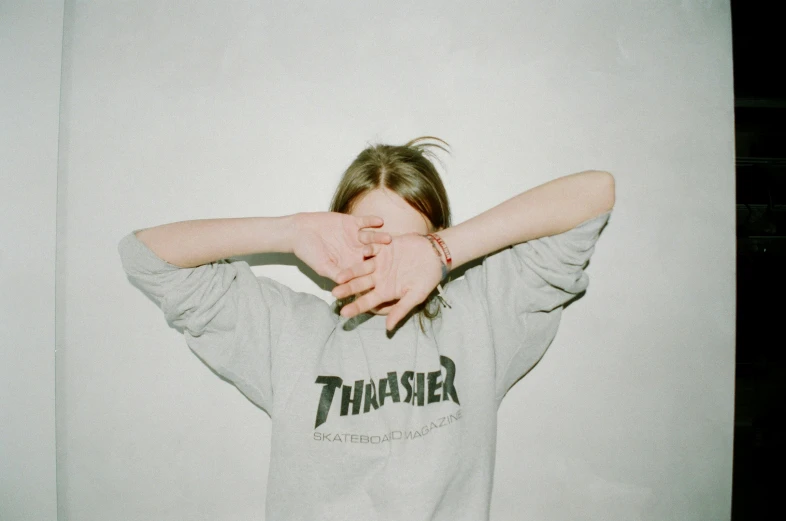 a woman wearing a thrash t - shirt holding her arms