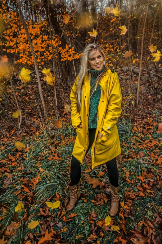 woman standing among yellow trees and leaves in the woods