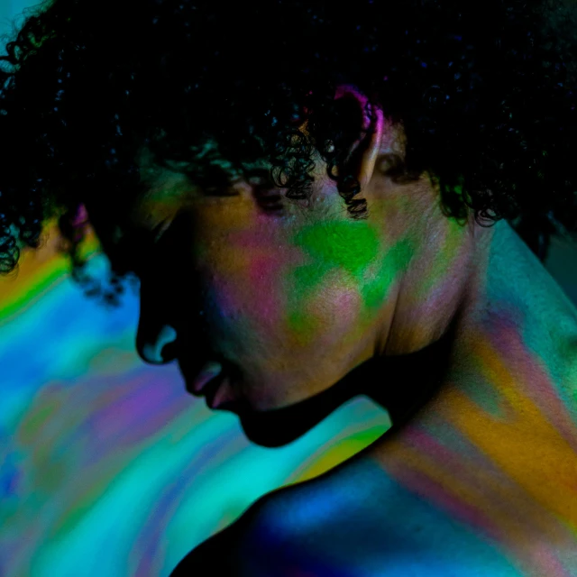 a black woman covered in brightly colored powder with a cellphone on her ear