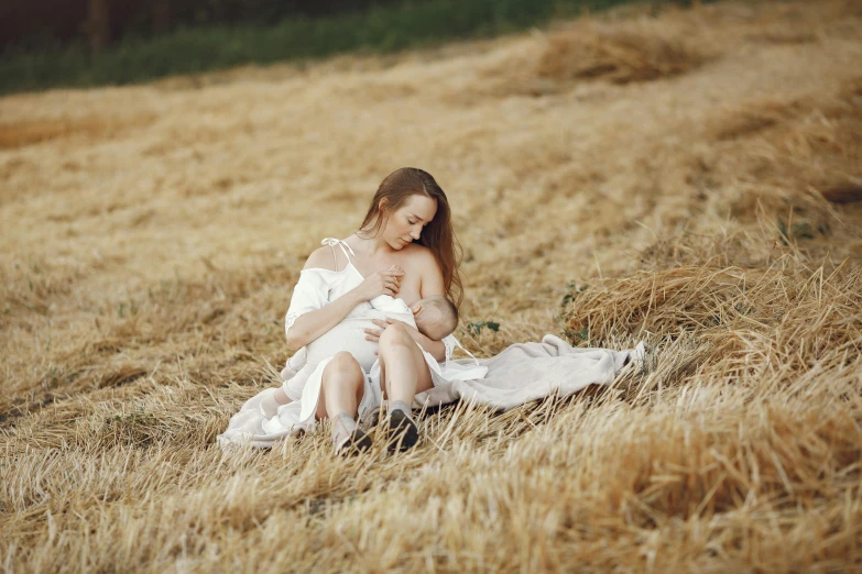 a woman in white dress sitting on grass in an open field