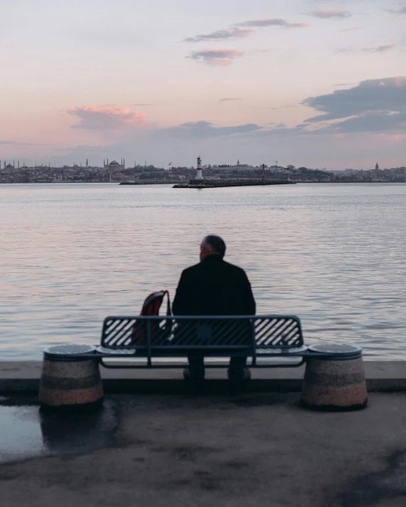 a man sitting on a bench next to the water