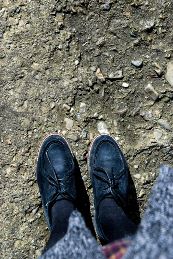two persons'feet in shoes standing on dirt ground