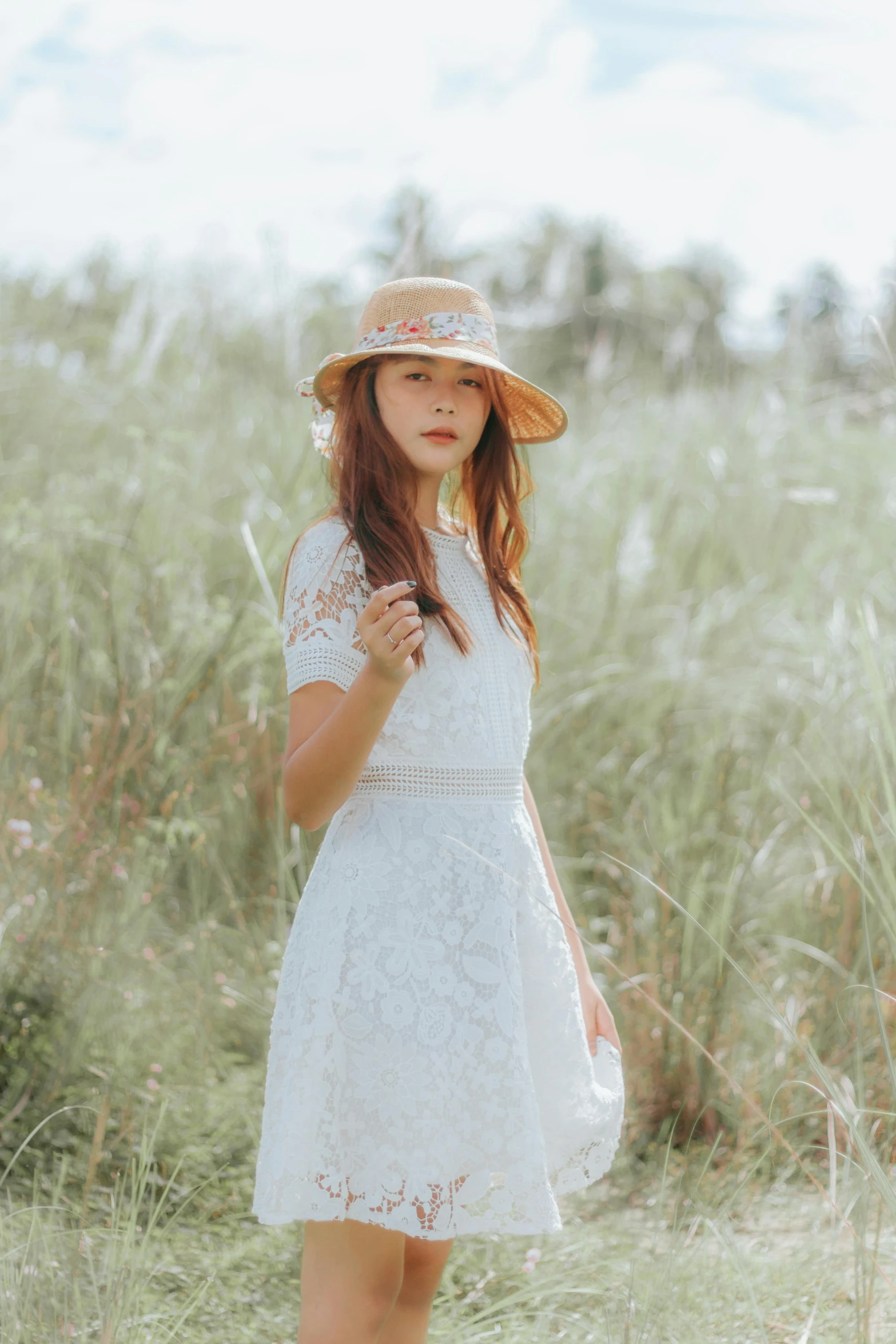 young woman wearing hat, standing in tall grass