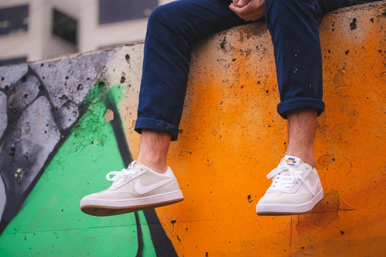 a man is sitting on the edge of an orange and green wall