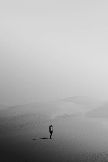 a black and white image of a person walking in the desert
