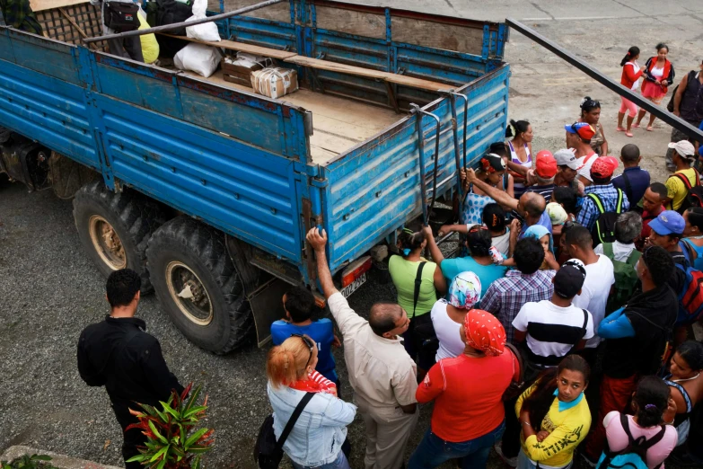 a group of people standing next to a blue truck