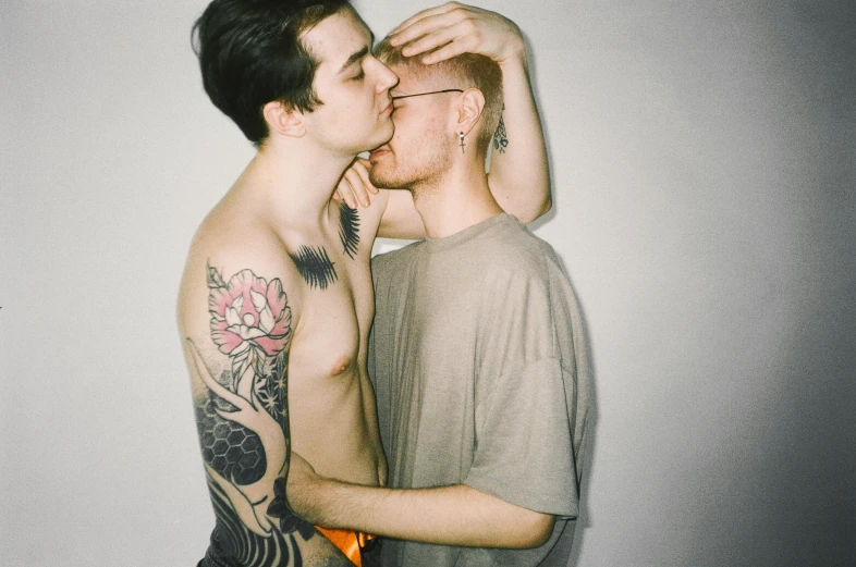 two guys kissing each other with tattoos