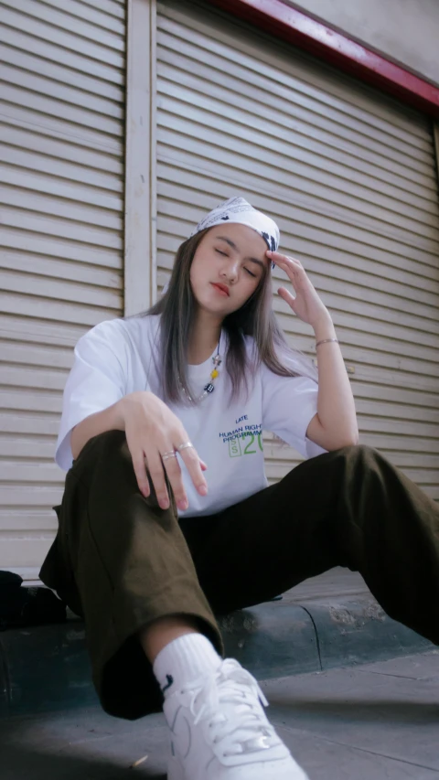 a girl is sitting on the ground, wearing white shoes and a white t - shirt