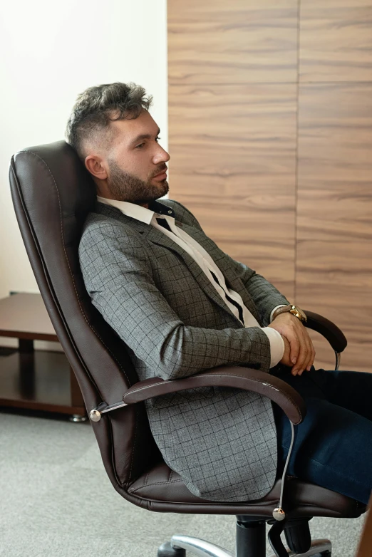 a man wearing a suit and tie is sitting in an office chair