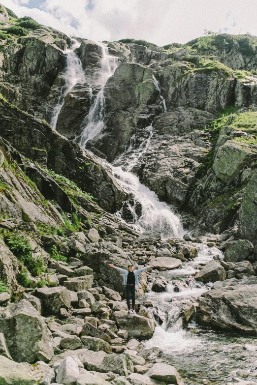 a man standing on rocks in front of a waterfall