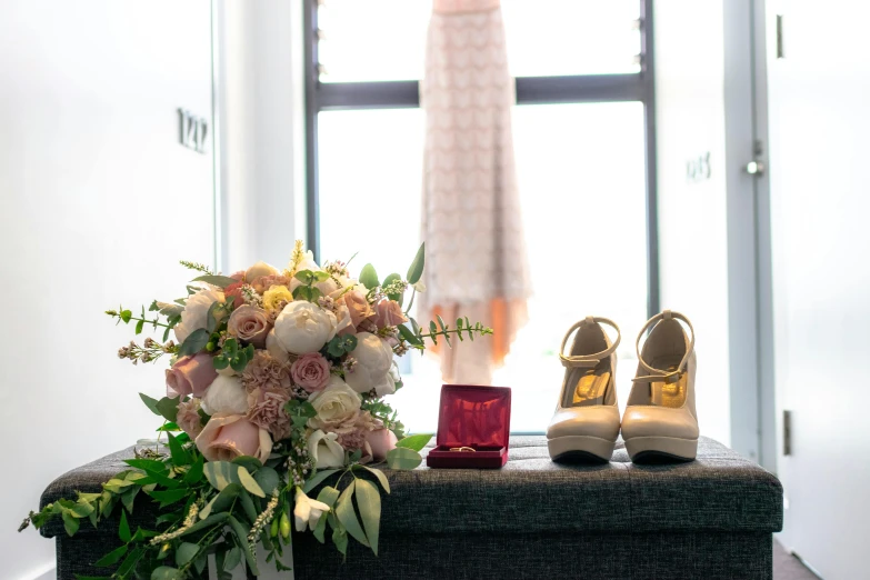 brides shoes and bouquet on bench near window