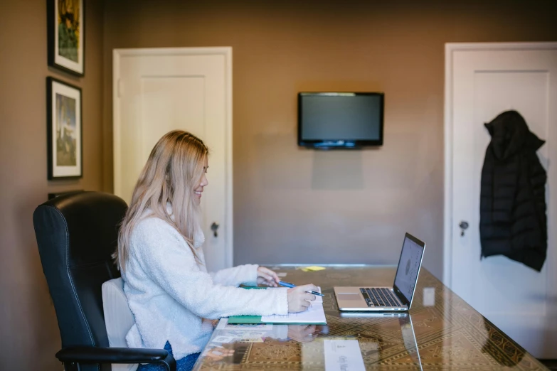 a woman sitting at a table working on a laptop computer