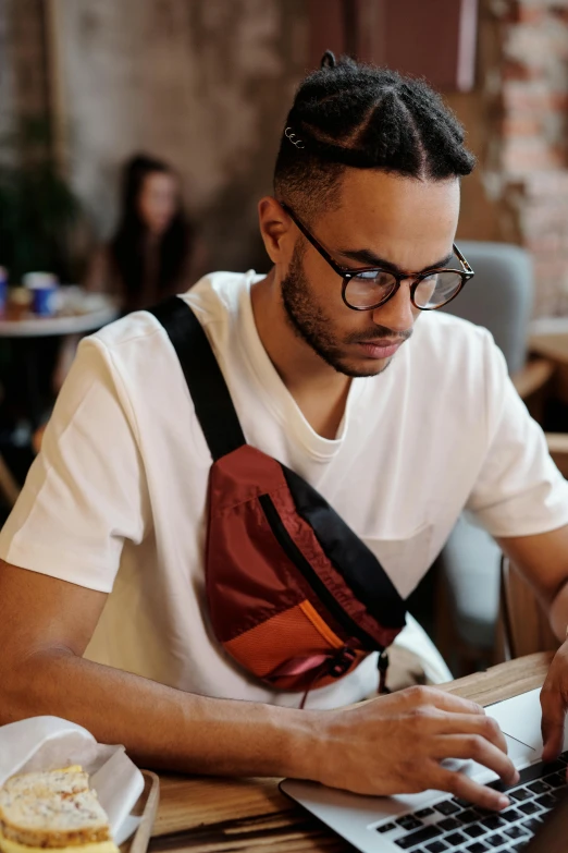 the man in glasses is sitting in front of a laptop