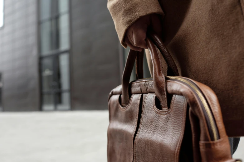 a man is carrying a brown bag on his arm