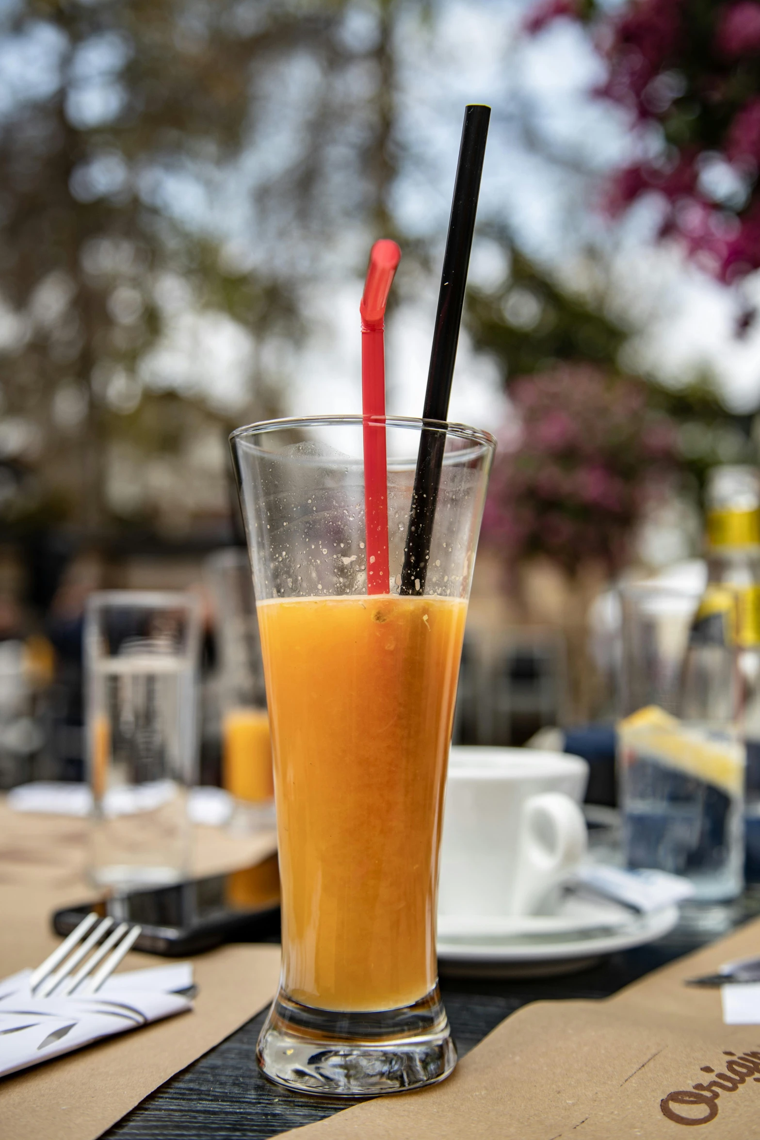 a glass of orange juice with two straws in it