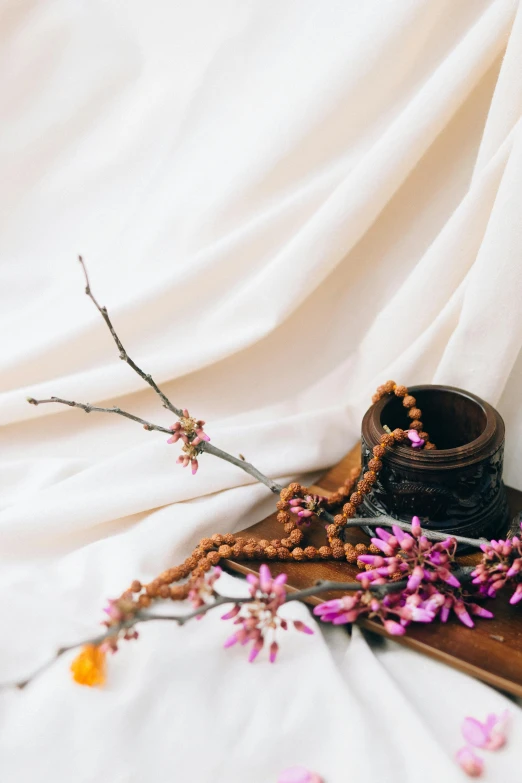 dried flowers and beads are laying on top of the sheet