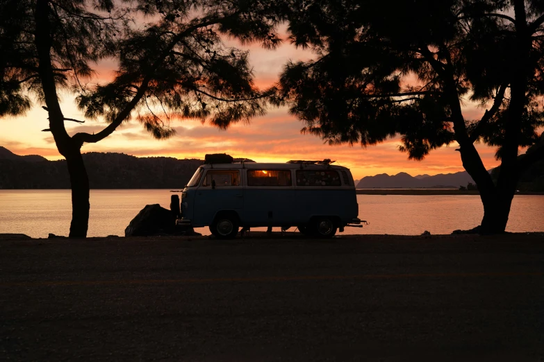 a white van parked under a tree next to the water