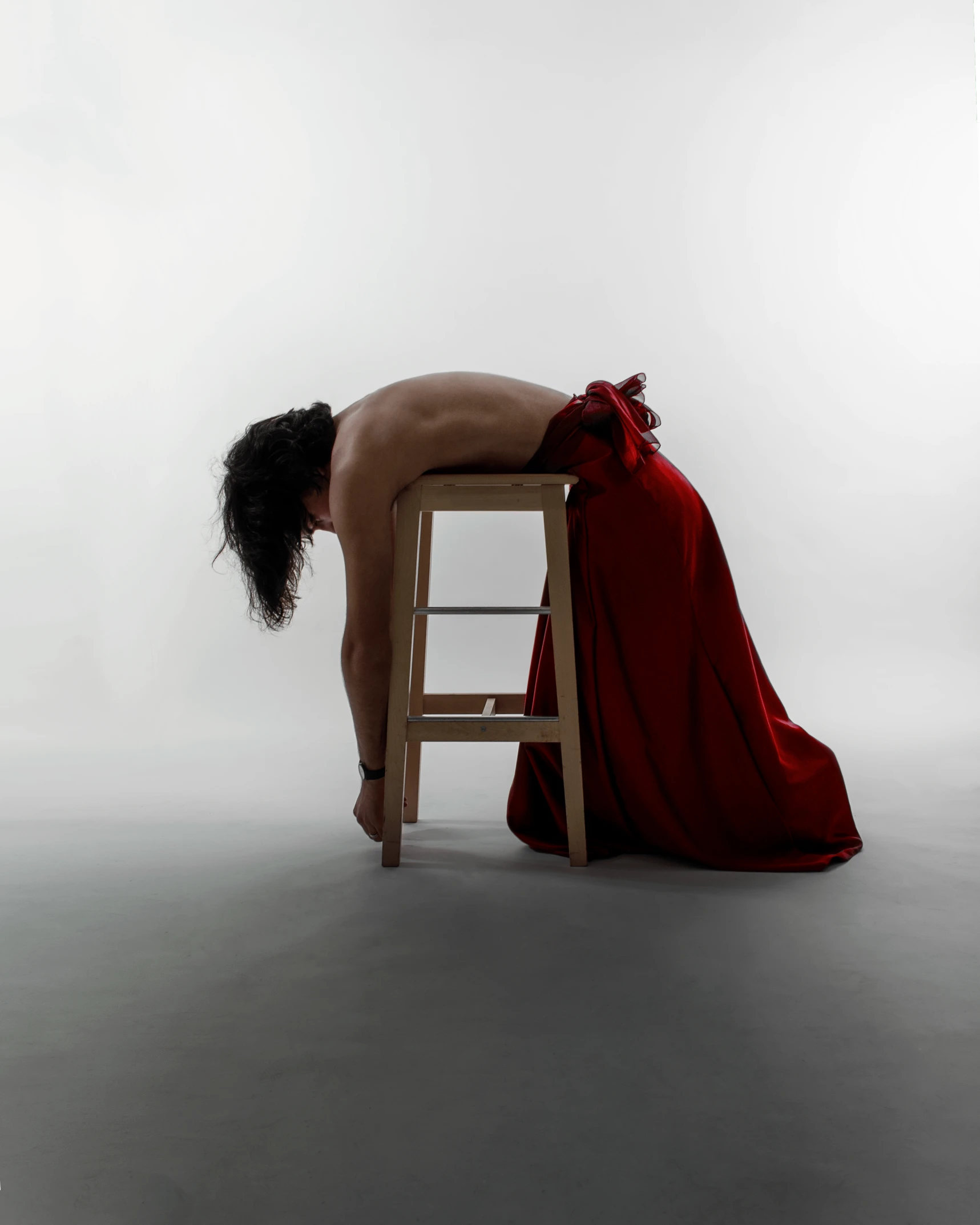 a woman in red shirt leaning over a stool