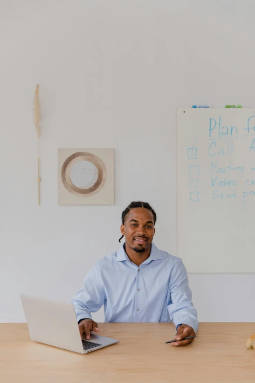 a man is sitting down on a desk in front of a laptop