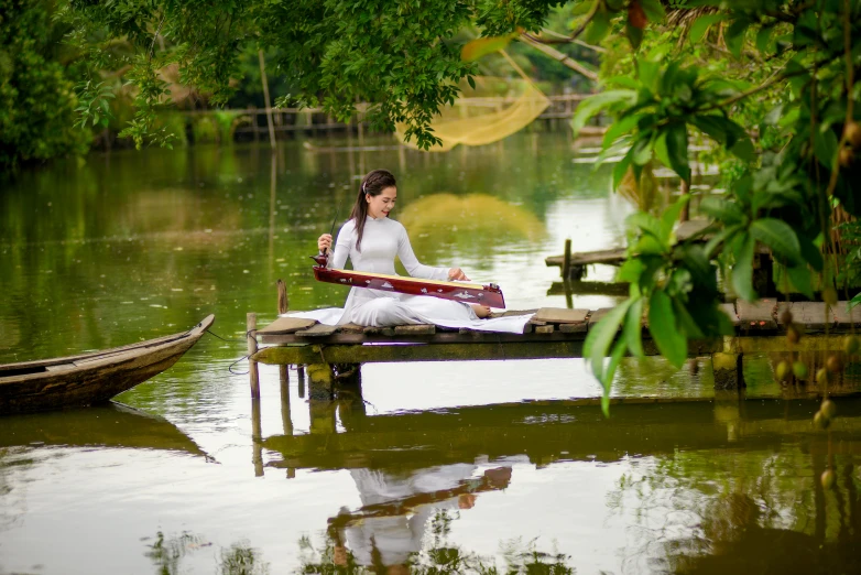 woman sitting on bench with a guitar over water