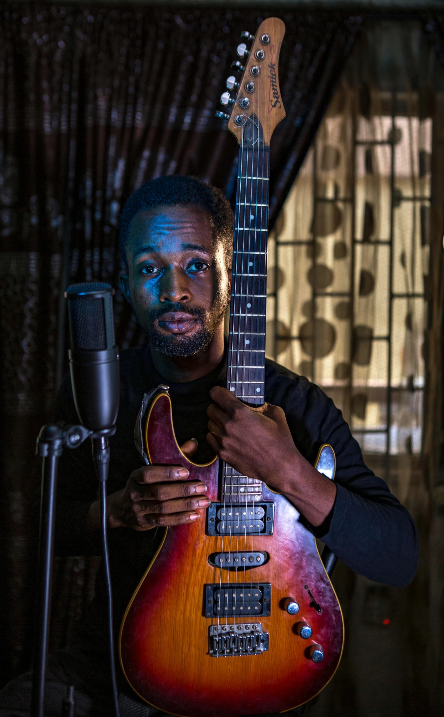 a man standing next to a guitar with the strings down